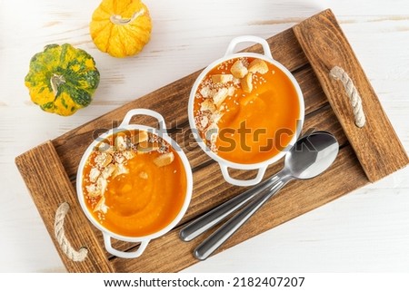 Pumpkin soup with croutons on wooden tray. Top view
