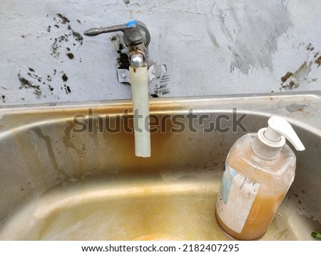 Close up photo of a water faucet and a bottle of hand soap on the front page of a clinic in Indonesia