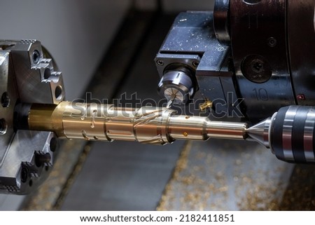 The multi-tasking CNC lathe machine  groove cutting the brass shaft parts by milling spindle. The high technology metal working with CNC turning machine. Royalty-Free Stock Photo #2182411851