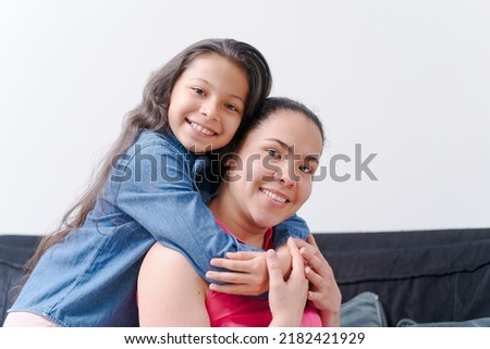 little girl hugging, kissing and smiling with her mother, young woman with her daughter