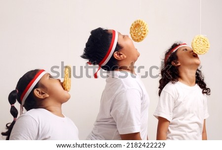 Asian kids celebrating indonesian independence day with cracker eating contest. Royalty-Free Stock Photo #2182422229