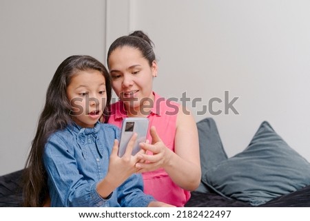 mother and daughter smiling and looking at a mobile phone