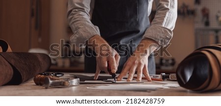 Tailor cobbler hold different rolls natural brown leather, working with textile in workshop. Royalty-Free Stock Photo #2182428759