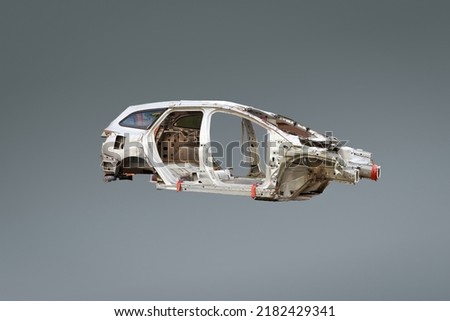 White modern damaged car chassis or body , outer metallic part of car against grey background, automobile steel junk Royalty-Free Stock Photo #2182429341
