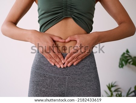 Close up of a multi-ethnic woman's hands on her stomach Royalty-Free Stock Photo #2182433619
