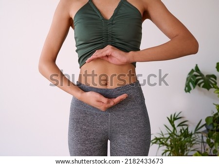 Cropped shot of a young multi-ethnic woman's stomach cupped by her hands Royalty-Free Stock Photo #2182433673
