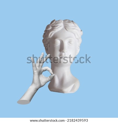 Antique female statue's head shows the ok gesture with hand isolated on a blue color background. Trendy abstact collage in magazine surreal style. 3d contemporary art. Modern design 