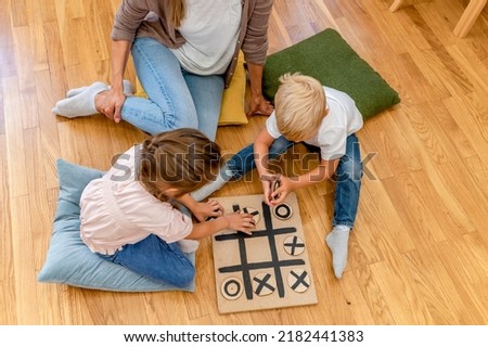 Mother playing with children a Tic-Tac-Toe game. Educational games for kids. Mother-children creative time together. Royalty-Free Stock Photo #2182441383