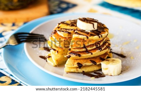 classic american breakfast. homemade banana pancakes on plate sprinkled powder and honey. A slide of hot pancakes with fresh bananas on a plate on the kitchen table . Pancake slide with honey topping Royalty-Free Stock Photo #2182445581