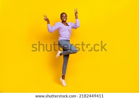 Full size photo of active pretty person stand one leg tip toe hands fingers show v-sign isolated on yellow color background