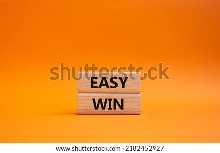 Easy win symbol. Wooden blocks with words 'Easy win'. Beautiful orange background. Business and 'Easy win' concept. Copy space.