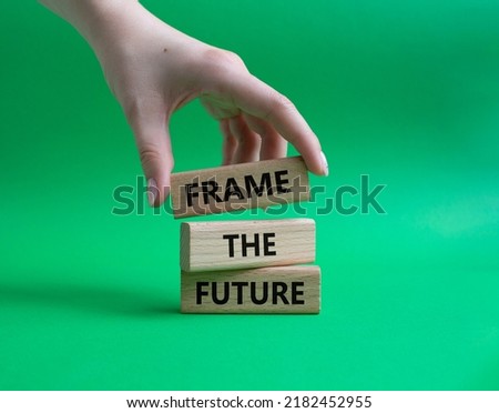 Frame the future symbol. Wooden blocks with words Frame the future. Beautiful green background. Businessman hand. Business and Frame the future concept. Copy space.