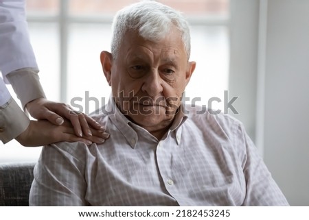 Doctor nurse hold caring hands on shoulder of sad elderly patient suffering of dementia alzheimer disease. Close up of physician help support disabled retired man patient. Medicare. Geriatric medicine Royalty-Free Stock Photo #2182453245