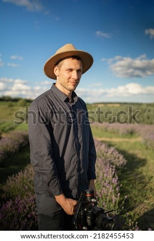 Happy photographer man holding camera in lavender field.