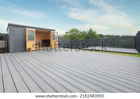 Ash grey composite decking built on two levels on a residential back garden with low voltage deck lights installed as well. Good Image for a landscape Gardiner Royalty-Free Stock Photo #2182483905