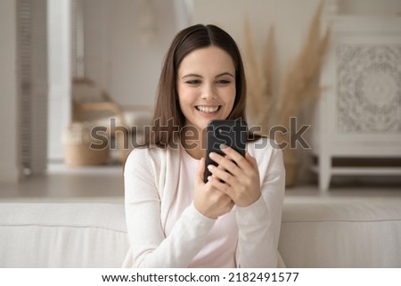 Leisure time. Cheerful happy young woman holding mobile telephone taking selfie on couch at home to post at social network profile, having pleasant talk by video link app, recording vlog using webcam