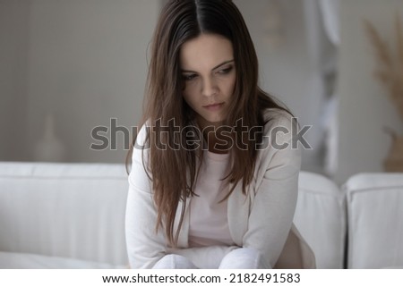 Bad streak. Sad suffering nervous millennial woman sitting on couch with her head down, looking aside feeling stress depression guilt shame, having health problems, unable to make difficult decision Royalty-Free Stock Photo #2182491583
