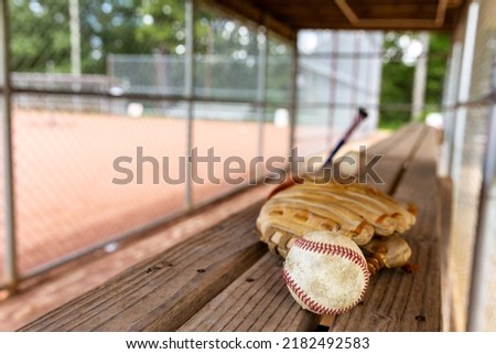 Baseball and glove on dugout bench with blurred background