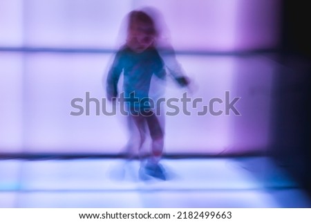 Children dance at the disco on glowing panels, blurry background. Blurry movement of people dancing.