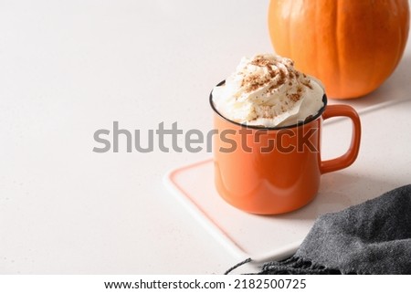 Halloween pumpkin latte coffee with whipped cream decorated spiders on white background. Horror funny food. Copy space. Close up.