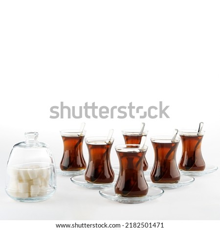 6 piece tea glass set with spoons and sugar bowl on a white background. There is tea in the cups. Tea lovers here