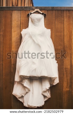 Wedding dress hanging on a wooden wall.