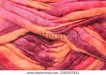 Close-up of colourful merino wool pink-orange striped background. Abstract handmade craft knitting yarn textured pattern flatlay. Holiday fall concept. Idea for felting, needlework, hobby. Mock up