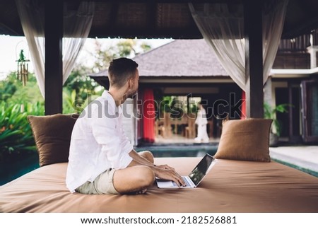 Contemplative male software developer thinking about graphic design for website during remote working at comfortable terrace, Caucaisan blogger with digital netbook doing distance job outdoors