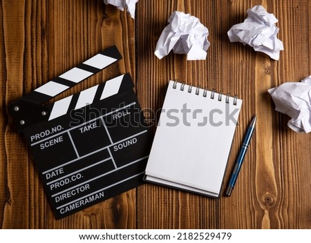 paper and a crumpled paper with cinematic clapperboard on a table top view