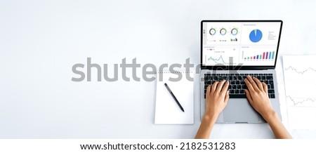 Panoramic photo of laptop with financial charts at screen, mockup for announcement, advertising. Top view, female hands lie on a laptop keyboard with a graphs at white screen, typing text. Copy-space Royalty-Free Stock Photo #2182531283