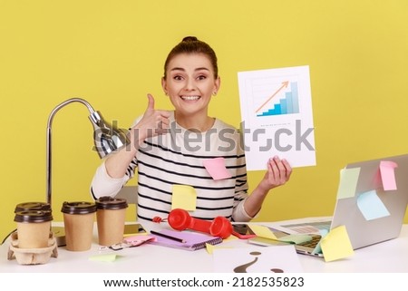 Portrait of smiling happy woman office manager looking at camera showing growth diagram, financial and economic growth of his business. Indoor studio studio shot isolated on yellow background.