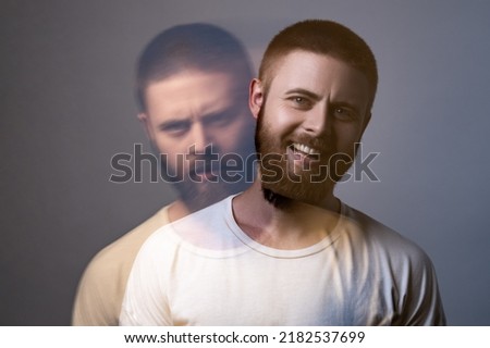Portrait of two-faced man in calm serious and happy expression. Different emotion inside and outside mood. Internally suffering, dissociative identity disorder. Double exposure. indoor, studio shot Royalty-Free Stock Photo #2182537699