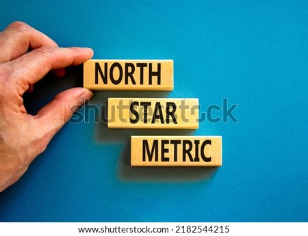 North star metric symbol. Concept words North star metric on wooden blocks on a beautiful blue table blue background. Businessman hand. Business finacial and north star metric concept. Copy space.