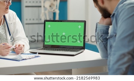 Young adult and medic using laptop with greenscreen at checkup visit, looking at isolated mockup template with blank copy space and chromakey background on display. Computer screen.