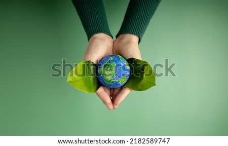 World Earth Day Concept. Green Energy, ESG, Renewable and Sustainable Resources. Environmental and Ecology Care. Hands of Person  Embracing Green Leaf and Craft Globe Royalty-Free Stock Photo #2182589747