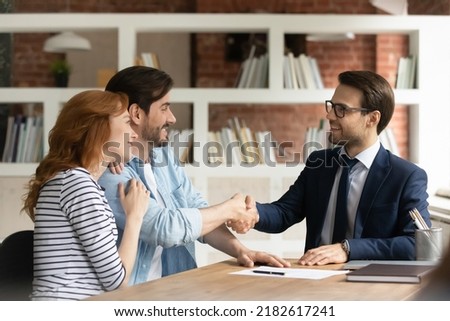 Couple handshake mortgage officer worker, accept bank loan terms and rates feel satisfied. Make financial deal, take credit, buying insurance cover, receive professional consult, sign contract concept Royalty-Free Stock Photo #2182617241