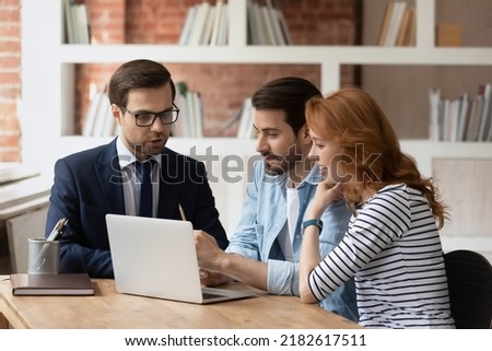 Real estate agent make offer for couple selects housing options, showing services presentation on laptop, choose new or secondary property for long term rental. Family and advisor discuss deal concept Royalty-Free Stock Photo #2182617511