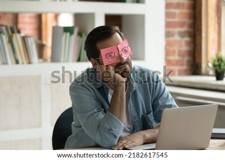Lazy office employee feels tired unmotivated sits at desk falls asleep hides his eyes under adhesive sticky notes, unproductive worker portrait, chronic fatigue, no inspiration and motivation concept Royalty-Free Stock Photo #2182617545