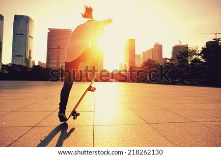 woman skateboarder skateboarding at sunrise city 