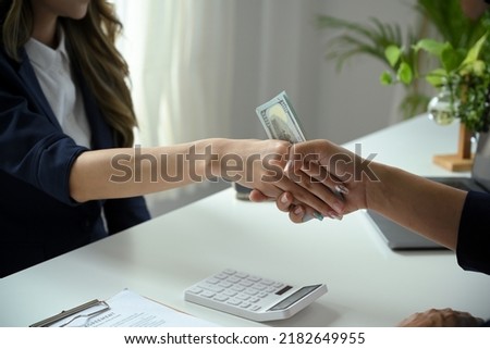 A female lawyer or business legal consultant receives a bribe or tribute from her client in the office. Corruption concept. cropped and close-up image