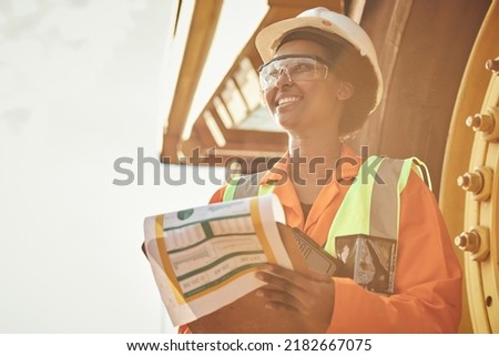 A young African woman mine worker is inspecting a large haul dump truck wearing personal protective wear Royalty-Free Stock Photo #2182667075