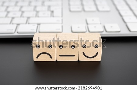 User service feedback, rating and customer review concept  Wooden blocks with facial expression icon and computer keyboard