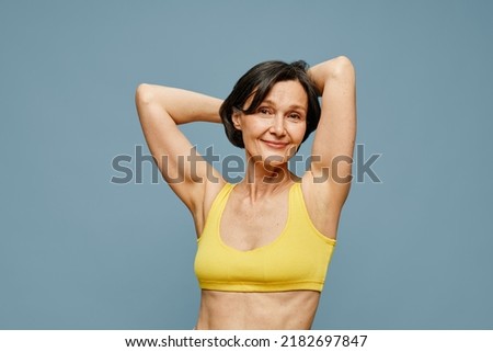Waist up portrait of carefree mature woman posing against pastel blue background, copy space Royalty-Free Stock Photo #2182697847