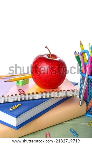 School stationery with apple and books on table against white background