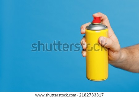 Close up cropped male hold in hand use yellow spray aerosol paint bottle can tin isolated on pastel plain light blue color wall background studio. Urban lifestyle street art concept Copy space mock up