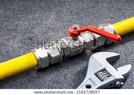 Gas tap connected to yellow gas pipe and wrench. Concept repairing gas pipeline Royalty-Free Stock Photo #2182738097