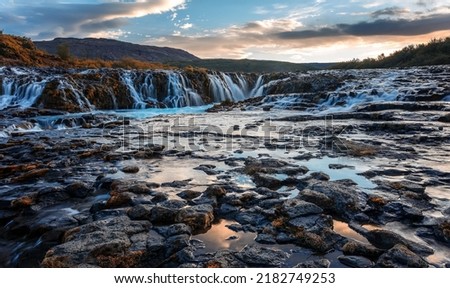 Scenic image of Iceland. Incredible nature landscape. Stunning view of Bruarfoss Waterfall. Azure water flows over stones. Bright midnight sun of Iceland. Iceland is a most popular place of travel.  Royalty-Free Stock Photo #2182749253