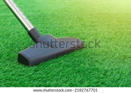 Selective focus of a vacuum cleaner on a sheet of artificial turf. Lawn care and maintenance. Easy to clean artificial greenery roll Royalty-Free Stock Photo #2182767701