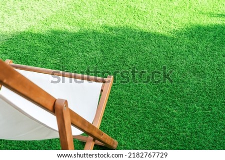 Close-up of a sun lounger on an artificial turf. Green lawn surface ideal for terraces, swimming pools or gardens Royalty-Free Stock Photo #2182767729