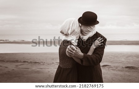 Faceless portrait of man kissing woman with white fabrics on their heads. Image in vintage retro style. Sepia toned and film grain added Royalty-Free Stock Photo #2182769175